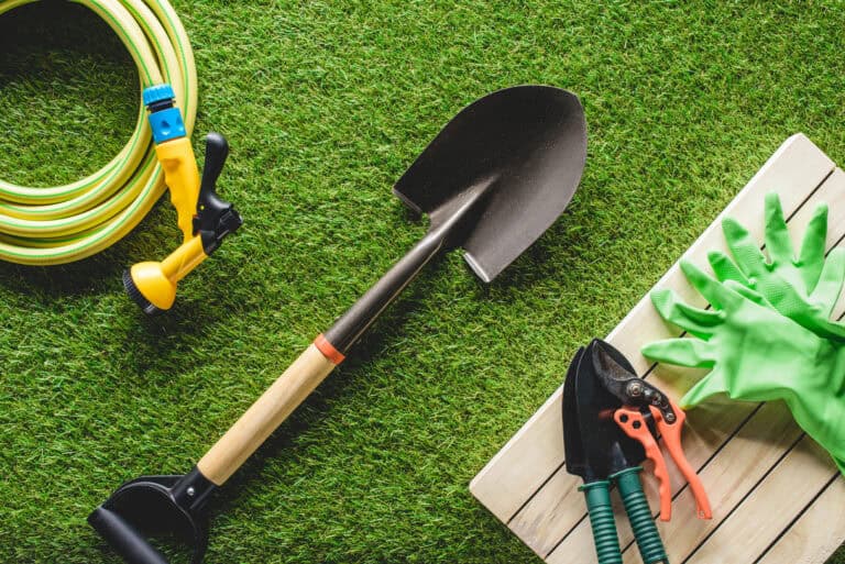 top view of hosepipe protective gloves and gardening tools on grass - losangelesgardenpros.com where do landscape contractors work where can you buy gravel landscape rock near me